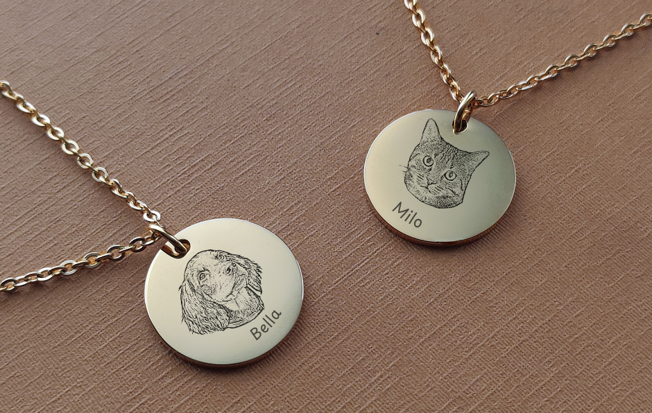 Two gold necklaces with engraved pet portraits on round pendants against a brown background.